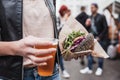 Close up of woman hands holding delicious organic salmon vegetarian burger and homebrewed IPA beer on open air beer an