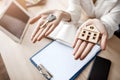 Close up woman hands holding key and wooden house. Documents tablet and phone on table. Royalty Free Stock Photo