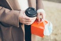 Close up of woman hands holding take away food and cup of coffee. Drinking hot beverage outdoors on the street. Selective focus, Royalty Free Stock Photo