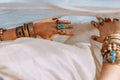 Close up of woman hands with lots of boho gem stone accessories covered with white fabric