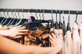 Close up woman hands make choice on colorful clothes on racks in a fashion boutique Royalty Free Stock Photo