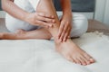 Close-Up of Woman Hands is Massaging Her Ankle on Bedroom, Young Adult having Legs Ache After Home Work. Healthcare and Medicine