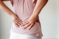 Close-Up of Woman Hands is Massaging Her Waist on  Gray Background, Young Adult having Backache After Home Work. Royalty Free Stock Photo