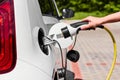 Close up woman hands plugging a power supply cable to electric car for charging at charging station outdoor. Royalty Free Stock Photo