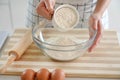 Close-up of woman hands pouring the flour into the bowl. Increasing price of wheat, flour and bread. Homemade bread preparation.