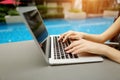 Close up woman hands pressing keyboard on laptop sunny day swimming pool Royalty Free Stock Photo