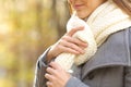 Woman hands putting on a scarf in a park in winter