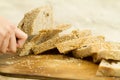 Close up of woman hands slicing a loaf of homemade bread with sesame seeds on a wooden cutting board in selective focus on wooden Royalty Free Stock Photo