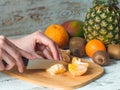 Close up Woman hands slicing tangerines on chopping board.