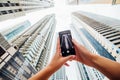 Close up of woman hands take phone on the iphone of skycrapers in modern arhitecture city. Low angle view