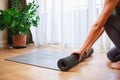 Close-up of woman hands unrolling roll black yoga mat for playing yoga at home