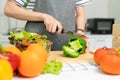 Close-up of woman hands use a knife to cut the bell pepper and various green leafy vegetables. Royalty Free Stock Photo