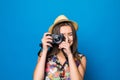 Close up of woman in hat on blue background taking a photo with digital camera Royalty Free Stock Photo
