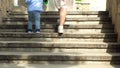 Close up of woman helping her little child boy to climb the stairs by holding his hand. Stock footage. Mother with small Royalty Free Stock Photo