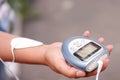 Close-up of a woman holding an electrode machine in her hand and with electrostimulator electrodes in the arm in a