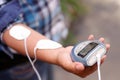 Close-up of a woman holding an electrode machine in her hand and with electrostimulator electrodes in the arm in a