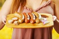 Close up of woman holding in her hands a grilled sausages on wooden cutting board, BBQ in the garden. Bavarian sausages Royalty Free Stock Photo