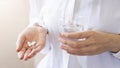 Close up woman holding pill in hand with water. Female going to take tablet from headache, painkiller, medication drinking clear w Royalty Free Stock Photo