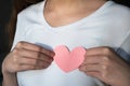 Woman in white t-shirt holding pink paper heart against chest Royalty Free Stock Photo