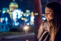 Close up of woman holding sparkler on the street. Girl with spar