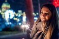 Close up of woman holding sparkler on the street. Girl with spar