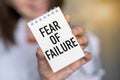 Close-up of woman holding a sticky note with text Fear of Failure a smiley face