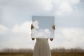 close up of a woman holding a surreal painting of the sky in front of her face, abstract concept