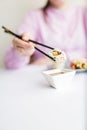 Close up of woman holding sushi roll with chopsticks above bowl full of soy sauce. Healthy traditional japanese meal concept Royalty Free Stock Photo