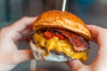 Close up woman holding taste cheeseburger with bacon. Gourmet burger, Fastfood Royalty Free Stock Photo