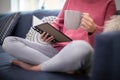 Close Up Of Woman With Hot Drink Relaxing On Sofa At Home Reading Journal Royalty Free Stock Photo