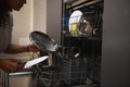 Close-up woman, housewife loading dirty dish inside a dishwasher, doing housework at home kitchen interior with Royalty Free Stock Photo