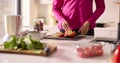 Close Up Of Woman In Kitchen Wearing Fitness Clothing Blending Fresh Ingredients For Healthy Drink