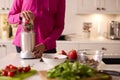 Close Up Of Woman In Kitchen Wearing Fitness Clothing Blending Fresh Ingredients For Healthy Drink