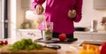 Close Up Of Woman In Kitchen Wearing Fitness Clothing Blending Fresh Ingredients For Healthy Drink