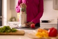 Close Up Of Woman In Kitchen Wearing Fitness Clothing Blending Fresh Ingredients For Healthy Drink
