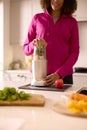 Close Up Of Woman In Kitchen Wearing Fitness Clothing Blending Fresh Ingredients For Healthy Drink