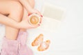 close-up of woman legs with fluffy slippers drinking a coffee and reading a good book