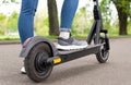 Close up woman legs standing on the electric kick scooter in summer day back view riding