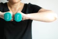 Close-up of woman lifting pastel-blue dumbbells weighing 1 kilogram in two hands place at center of chest Royalty Free Stock Photo