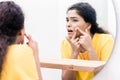 Woman looking in mirror squeezing pimple Royalty Free Stock Photo