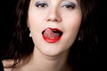 Close-up woman looks straight into the camera on a black background. expresses different emotions, showing tongue Royalty Free Stock Photo