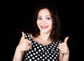 Close-up woman looks straight into the camera on a black background. shows various signs hands. expresses different