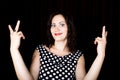 Close-up woman looks straight into the camera on a black background. shows various signs hands. expresses different