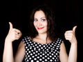 Close-up woman looks straight into the camera on a black background. shows various signs hands. expresses different