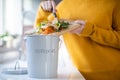 Close Up Of Woman Making Compost From Vegetable Leftovers In Kitchen