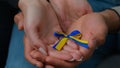 Close-up woman and man hands of multiracial family couple husband wife holding yellow blue colors ribbon national symbol