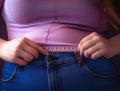 Close up of woman measuring her waist size with tape measure. Overweight concept