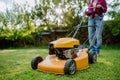 Close-up of woman mowing grass with lawn mower in the garden, garden work concept. Royalty Free Stock Photo