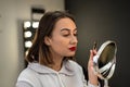 close-up of a woman paints her eyebrow with paint with a bone to a small make-up mirror. Royalty Free Stock Photo