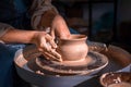 Close-up A woman potter in beautifully sculpts a deep bowl of brown clay and cuts off excess clay on a potter`s wheel in